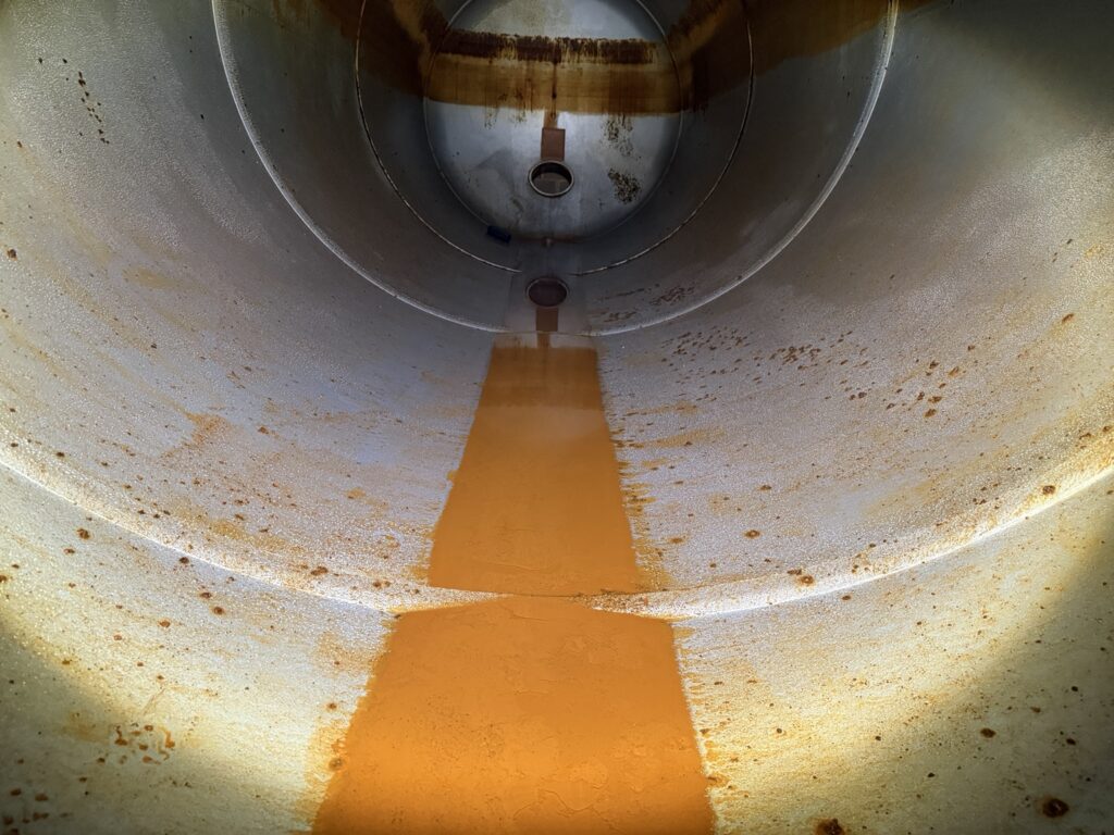 Interior view of drained fire protection water storage tank during internal inspection showing flow patterns and coating condition